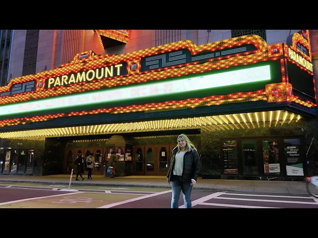 A UMass Boston student stands under the Paramount Theater marquis in Downtown Boston