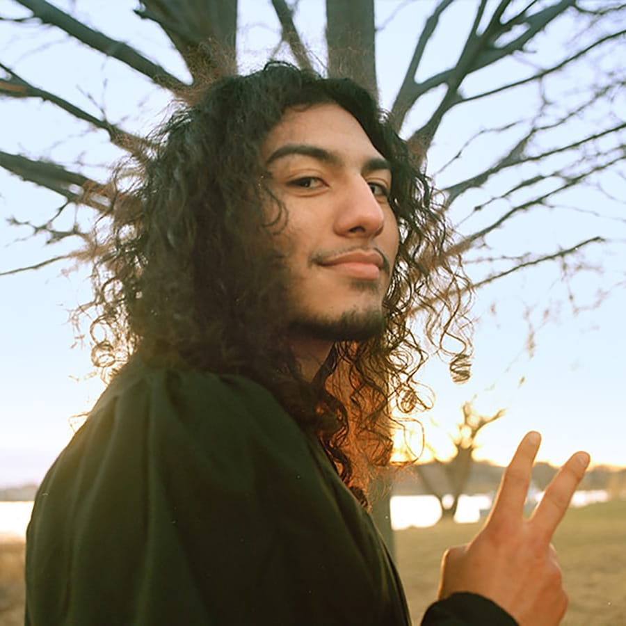 Student makes peace symbol with hand facing camera.