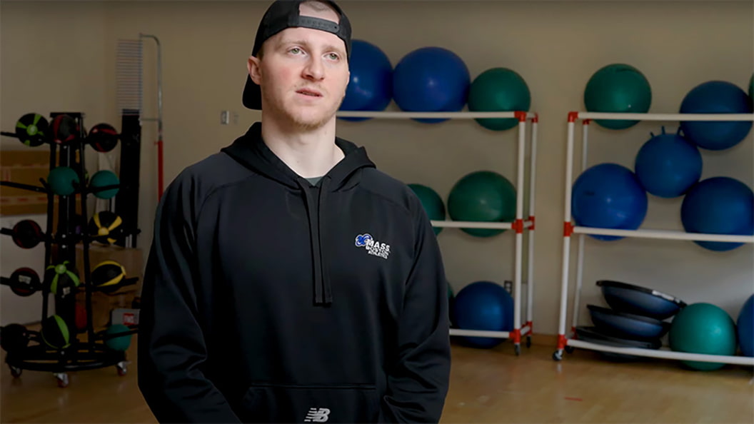 An Exercise & Health Sciences Student stands in front of exercise equipment