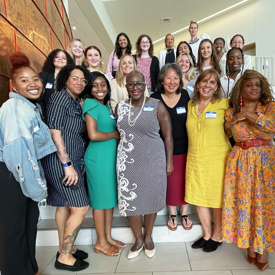 UMass Boston GLPP program students and staff smile together standing on a staircase