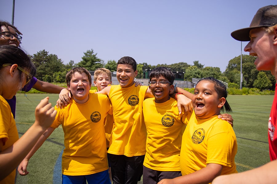 5 kids in yellow Camp Shriver shirts in friendly group embrace