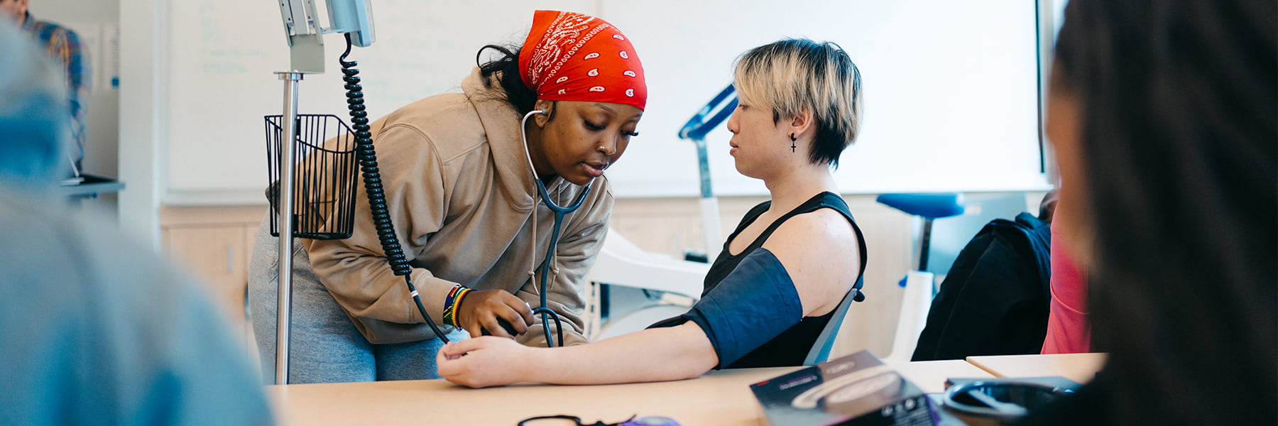 Student takes another students blood pressure in classroom.
