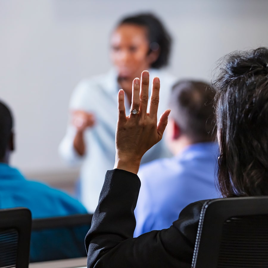 back of head of teacher raising hand to ask question