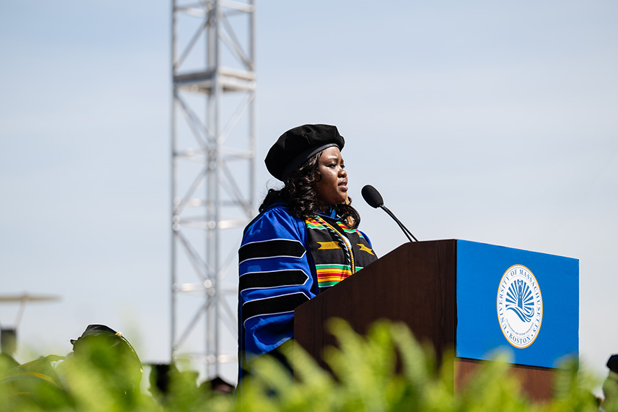 Charlotte Kyeremah standing at podium on stage at graduate commencement