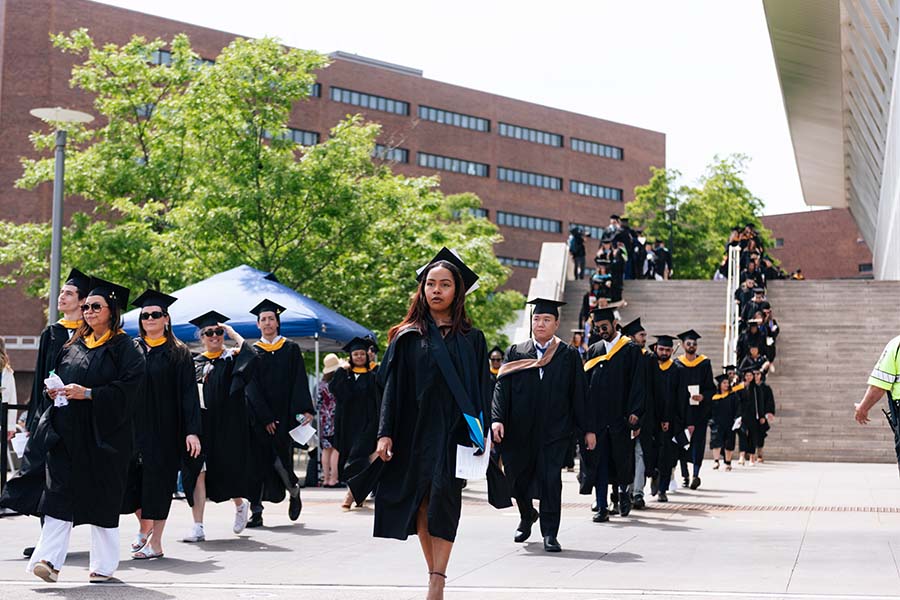 Graduate students walking to commencement ceremony gap and gown