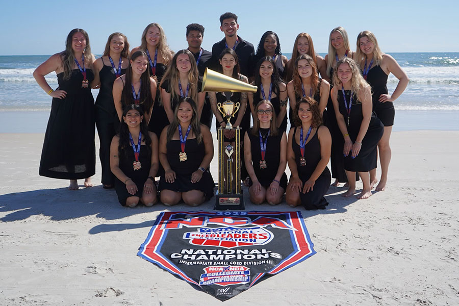 UMass Cheerleader NCA National Title Win Trophy students posing on the beach