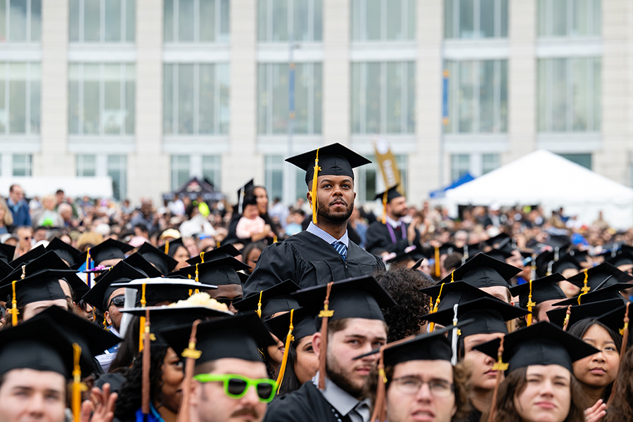 Undergraduate student stands in crowd at commencement