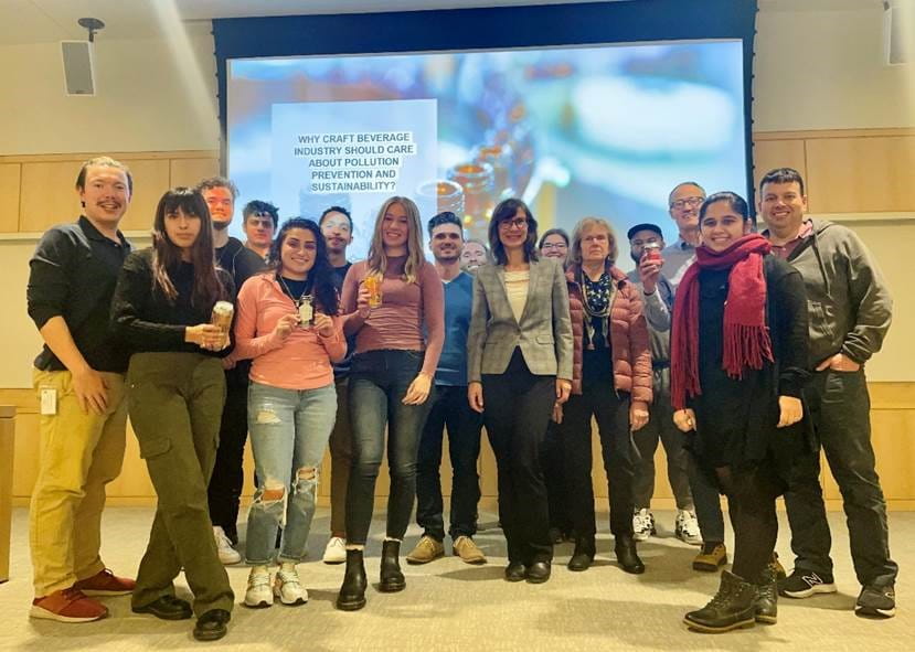 Grad students in Introduction to Environmental Management, along with lecturer Vesela Velva, stand in front of a screen displaying the words 