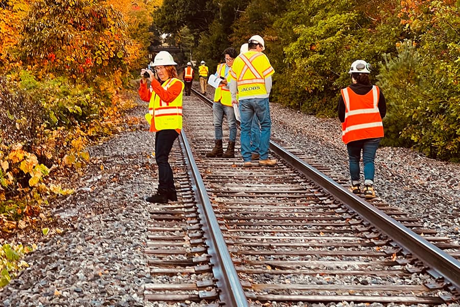 Workers in Safety vests work along the Cape Code Rail tracks.