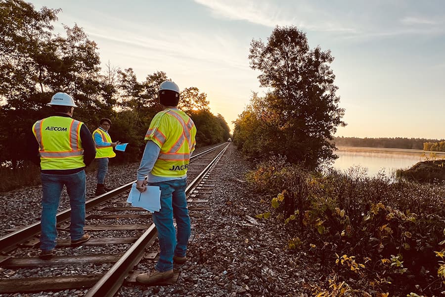Workers in safety vests work along the Cape Cod Railway tracks.