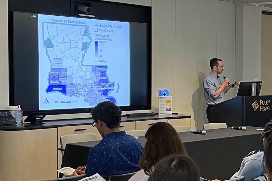 Sustainable Solutions Lab climate adaptation forum presenter at podium in classroom map on screen.
