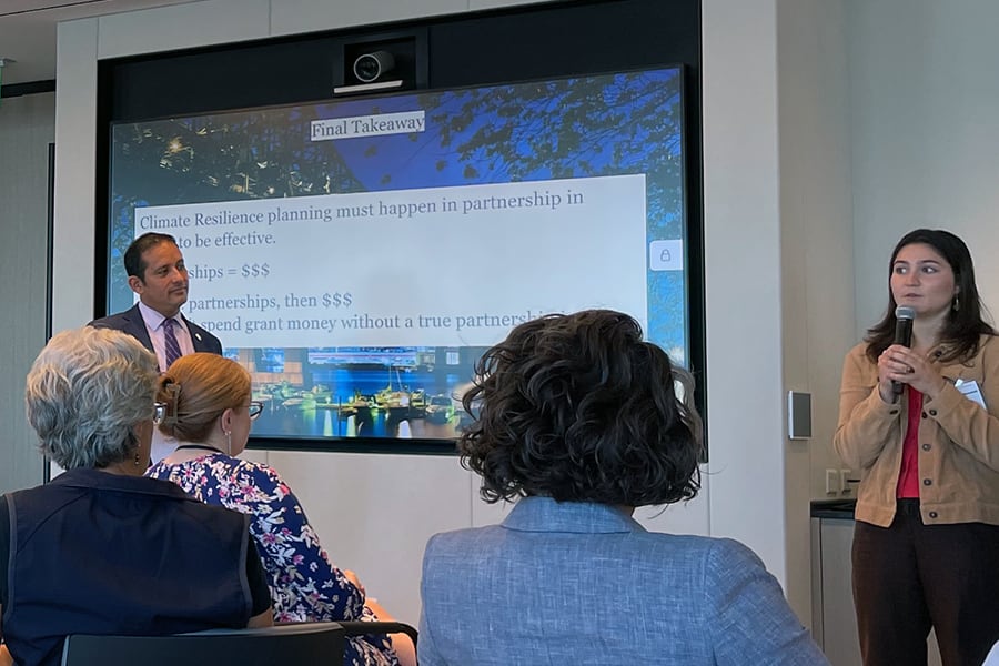 Sustainable Solutions Lab climate adaptation forum speaks in front of a digital screen.