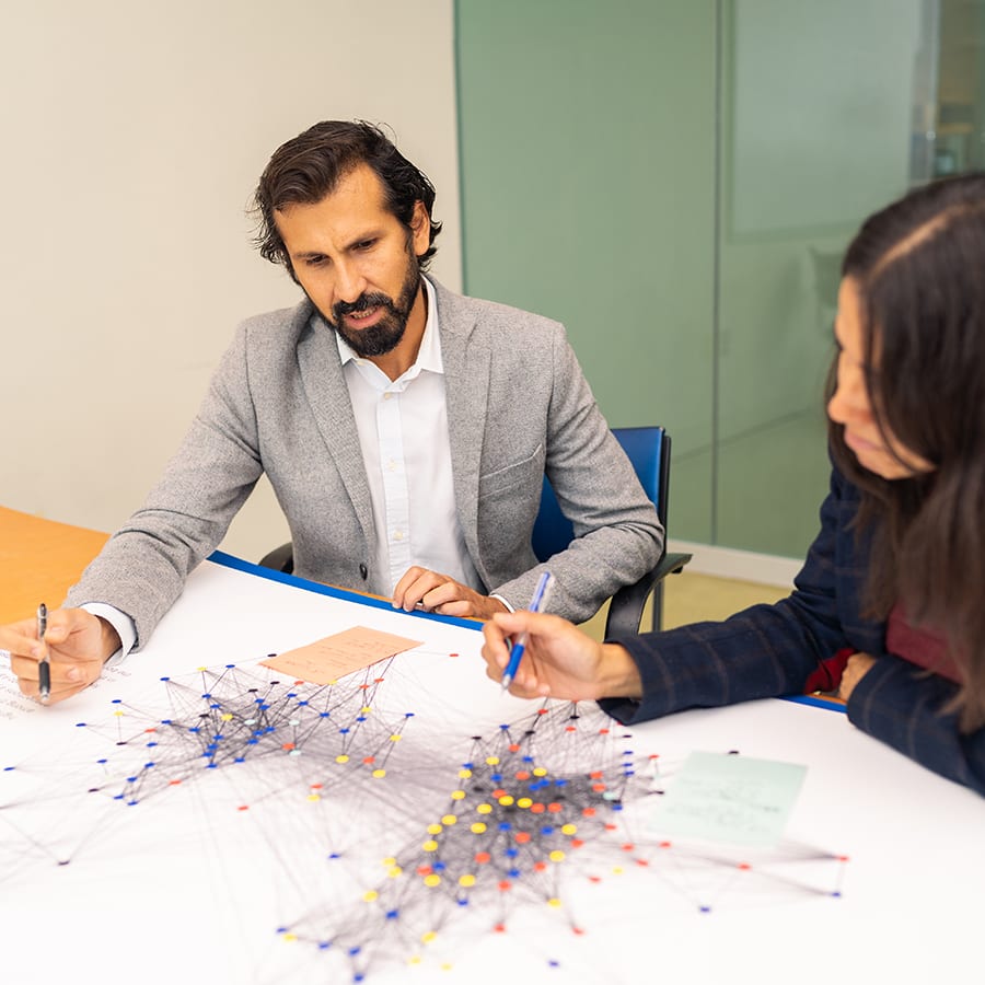 Faculty look at map with lines on conference table.