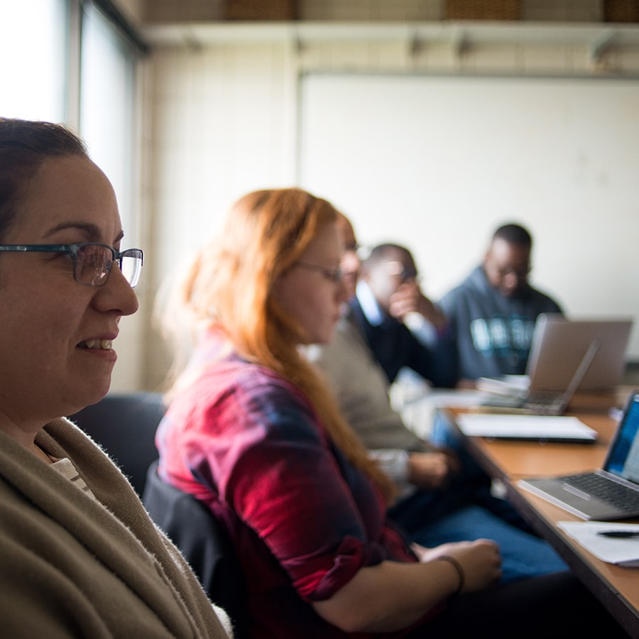 graduate students and team sitting around a desk with laptops - by Ed Collier photographer